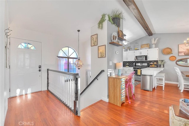 foyer featuring vaulted ceiling with beams, a notable chandelier, and light wood-type flooring