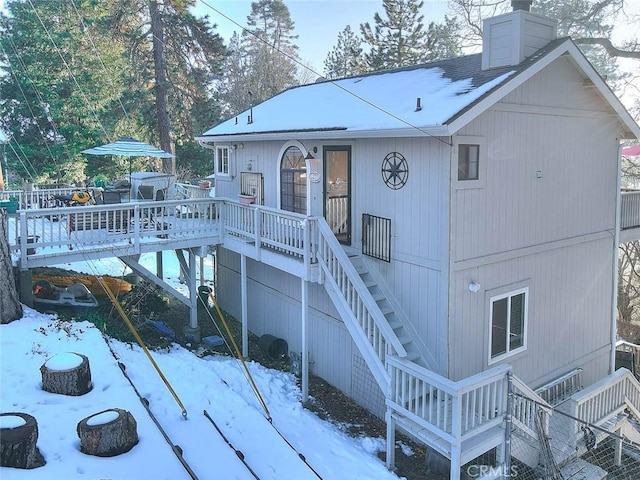 snow covered rear of property featuring a wooden deck