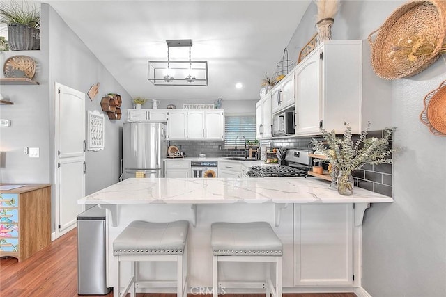 kitchen featuring decorative light fixtures, stainless steel fridge, kitchen peninsula, and range