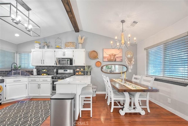 kitchen featuring appliances with stainless steel finishes, decorative light fixtures, sink, white cabinets, and an inviting chandelier