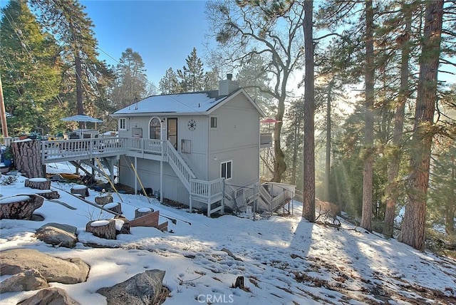 snow covered back of property with a deck