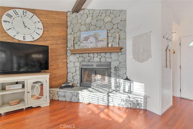 living room featuring beam ceiling, wood-type flooring, and a fireplace