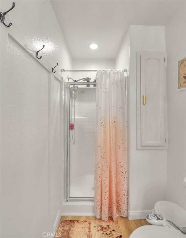 bathroom with wood-type flooring, toilet, and a shower with shower curtain