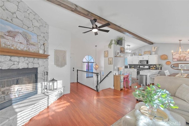 living room with hardwood / wood-style flooring, a fireplace, lofted ceiling with beams, and ceiling fan with notable chandelier