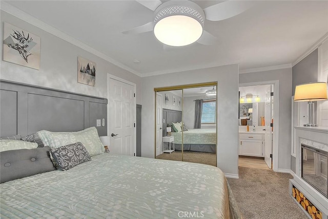 carpeted bedroom featuring crown molding, ceiling fan, ensuite bathroom, and a closet