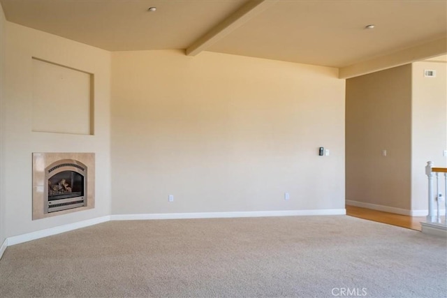 unfurnished living room featuring a tile fireplace, carpet flooring, heating unit, and vaulted ceiling with beams