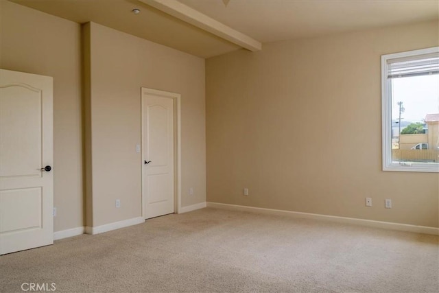 unfurnished room featuring beamed ceiling and light colored carpet