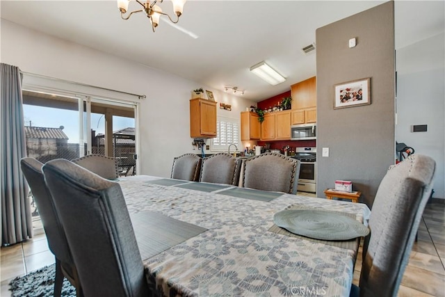 dining room featuring light tile patterned flooring, lofted ceiling, and a notable chandelier