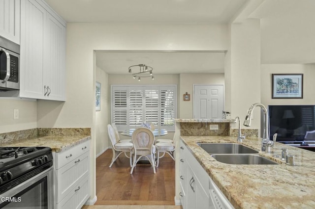 kitchen featuring white cabinetry, light stone countertops, sink, and light hardwood / wood-style flooring