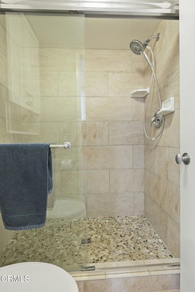 bathroom featuring toilet and a shower with shower door