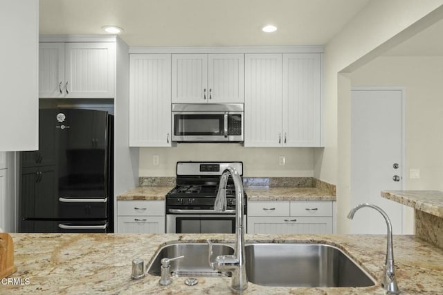 kitchen with white cabinetry, sink, stainless steel appliances, and light stone countertops