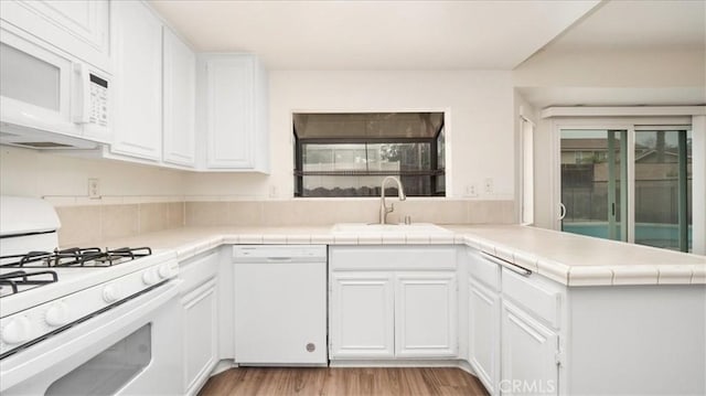 kitchen featuring white cabinetry, sink, white appliances, and kitchen peninsula