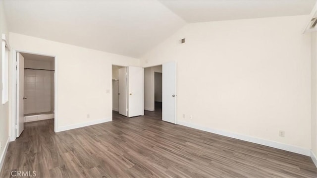 unfurnished bedroom featuring a walk in closet, dark hardwood / wood-style flooring, and high vaulted ceiling