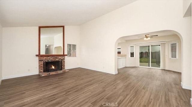 unfurnished living room featuring dark hardwood / wood-style flooring, a brick fireplace, high vaulted ceiling, and ceiling fan