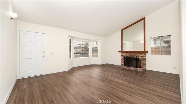 unfurnished living room with vaulted ceiling, a brick fireplace, and dark hardwood / wood-style flooring