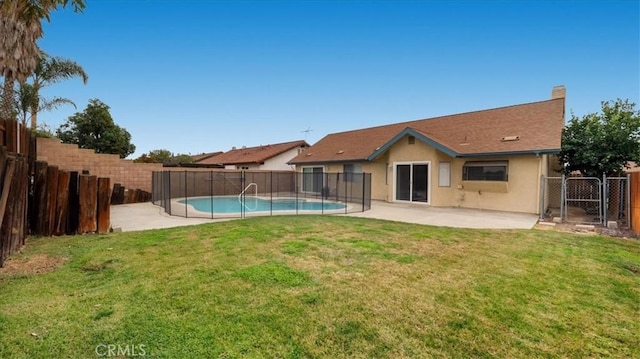 back of house featuring a fenced in pool, a lawn, and a patio