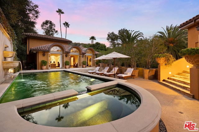 pool at dusk featuring a patio