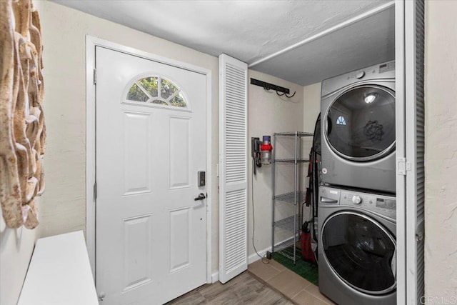 laundry room featuring stacked washer and dryer and wood-type flooring