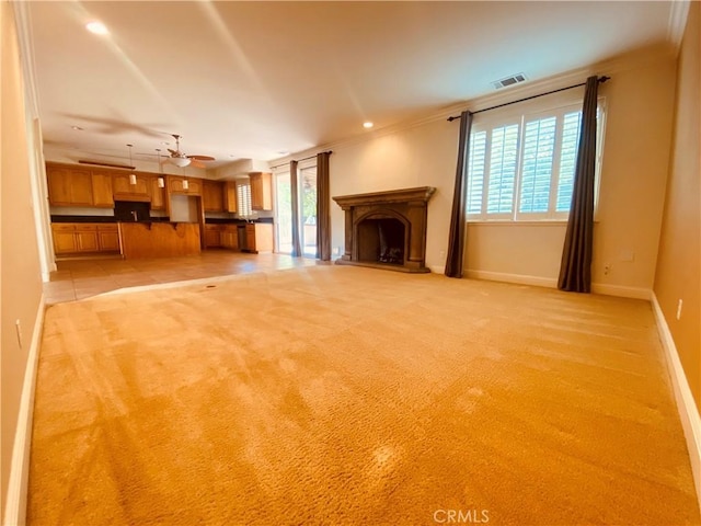 unfurnished living room featuring ornamental molding, plenty of natural light, light colored carpet, and ceiling fan