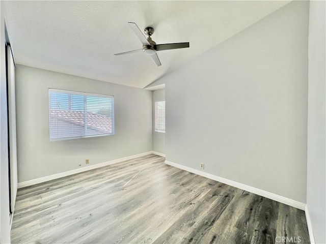 spare room with wood-type flooring, ceiling fan, and vaulted ceiling