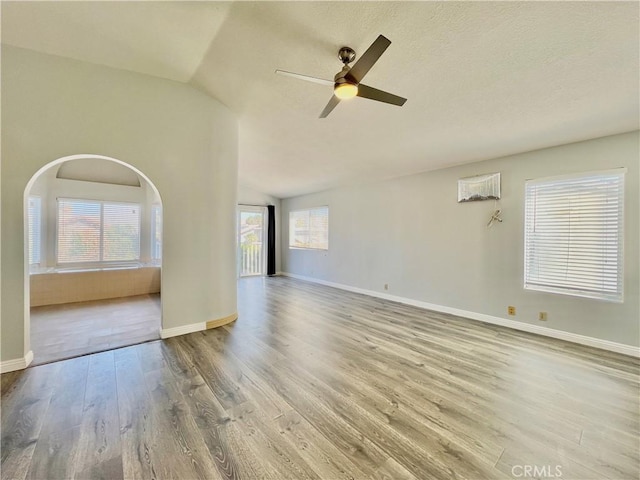 unfurnished living room featuring ceiling fan, vaulted ceiling, and light wood-type flooring