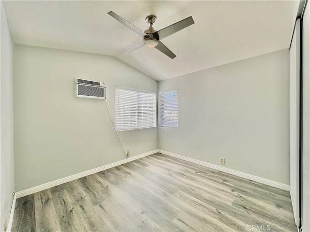 spare room featuring vaulted ceiling, a wall mounted AC, ceiling fan, and light hardwood / wood-style floors