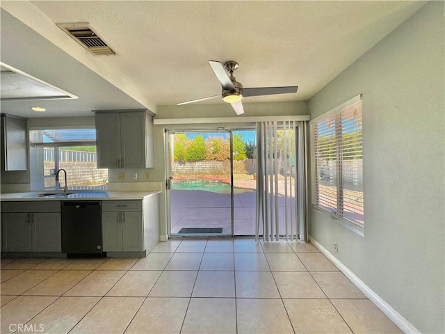 kitchen with light tile patterned flooring, black dishwasher, sink, and gray cabinetry