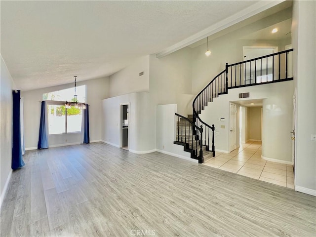 interior space featuring high vaulted ceiling, an inviting chandelier, and light hardwood / wood-style flooring