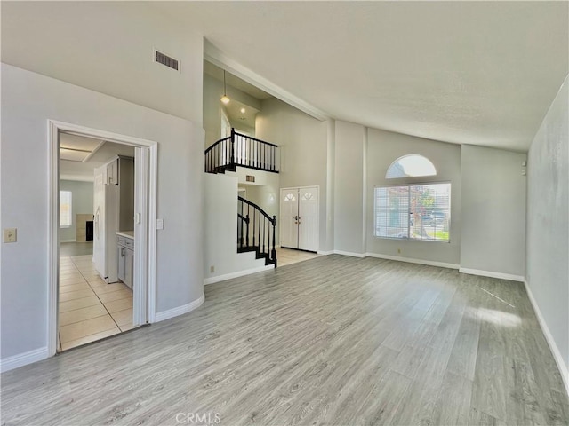 unfurnished living room featuring light hardwood / wood-style flooring and high vaulted ceiling