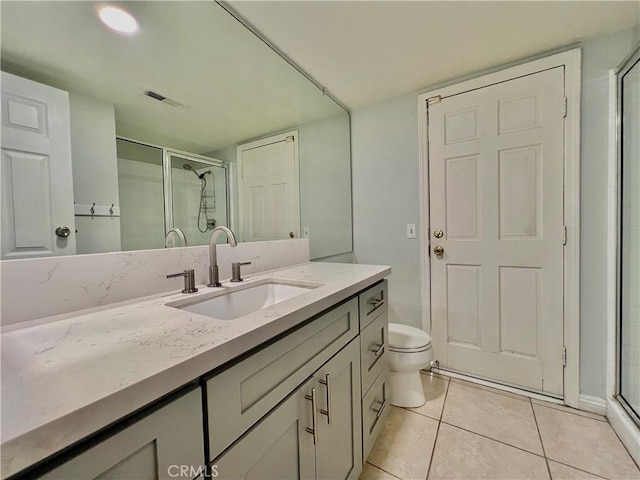 bathroom featuring tile patterned flooring, vanity, an enclosed shower, and toilet