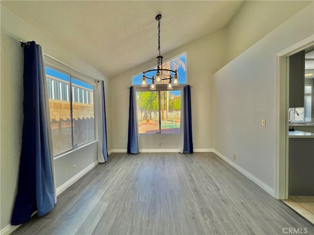 unfurnished dining area featuring an inviting chandelier, lofted ceiling, sink, and wood-type flooring