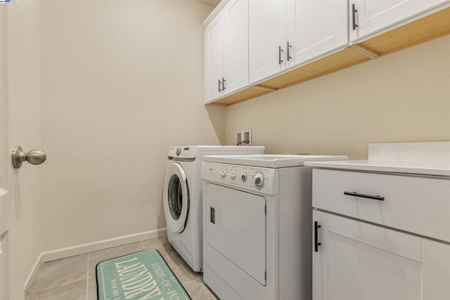 laundry room featuring light tile patterned flooring, cabinets, and washer and clothes dryer