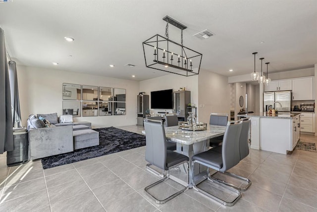 dining space featuring sink, light tile patterned floors, and a notable chandelier