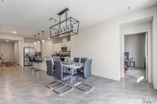 dining space with light tile patterned flooring, sink, and a textured ceiling