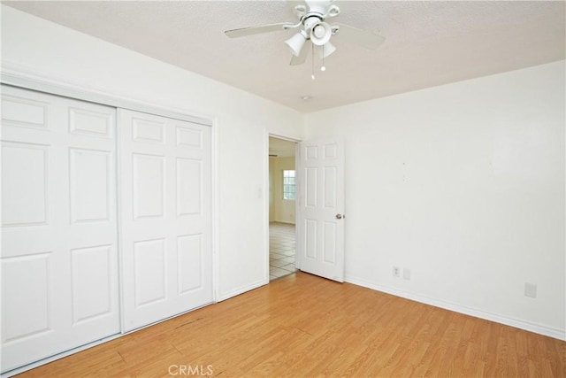 unfurnished bedroom with ceiling fan, a closet, and light wood-type flooring