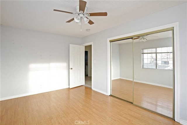 unfurnished bedroom featuring ceiling fan, a closet, and light wood-type flooring