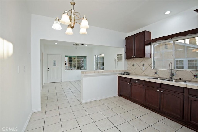 kitchen featuring sink, tile countertops, decorative light fixtures, dark brown cabinets, and backsplash