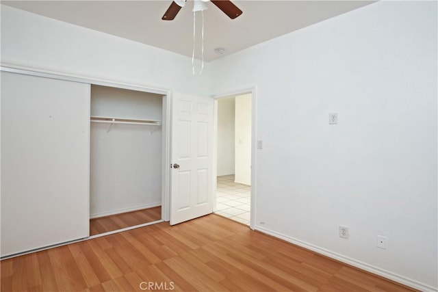 unfurnished bedroom featuring ceiling fan, light wood-type flooring, and a closet