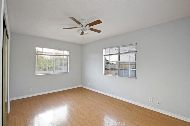 interior space featuring ceiling fan, a closet, light hardwood / wood-style floors, and multiple windows