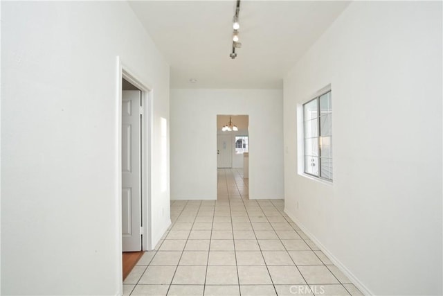 hallway with light tile patterned flooring, rail lighting, and a chandelier