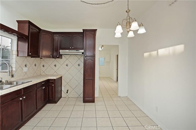 kitchen featuring sink, an inviting chandelier, backsplash, light tile patterned flooring, and decorative light fixtures