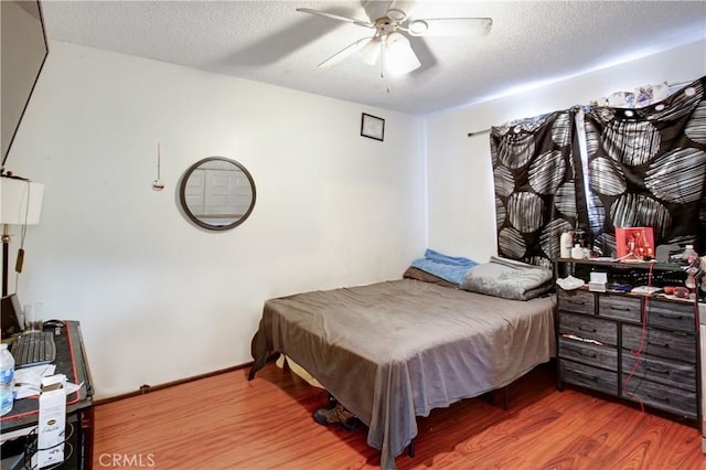 bedroom featuring hardwood / wood-style floors, a textured ceiling, and ceiling fan