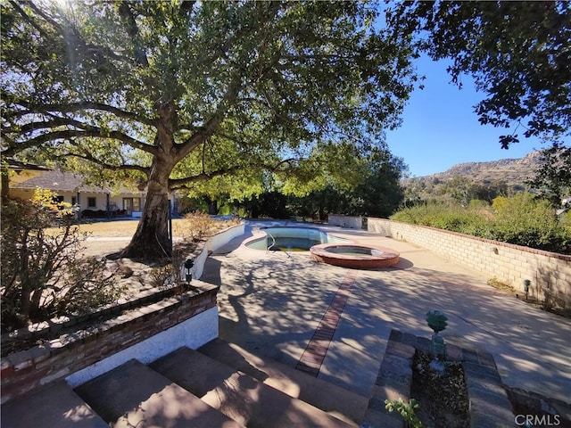 view of patio / terrace with an in ground hot tub and a mountain view