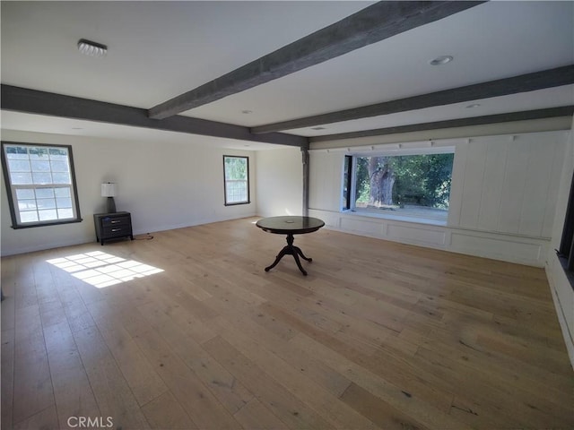 interior space with beam ceiling and light hardwood / wood-style flooring