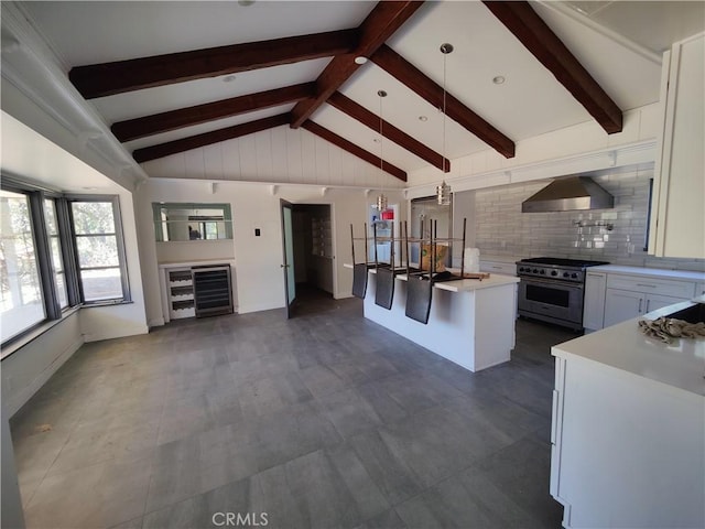 kitchen featuring wall chimney exhaust hood, hanging light fixtures, a center island with sink, high quality appliances, and white cabinets