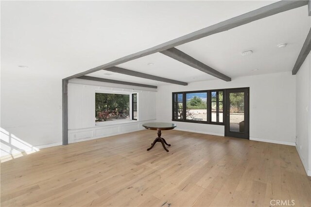 empty room with beamed ceiling and light hardwood / wood-style floors