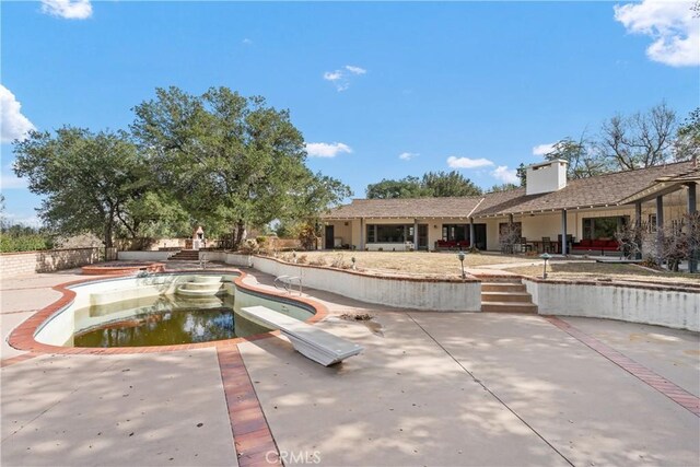 view of swimming pool with a patio and a diving board