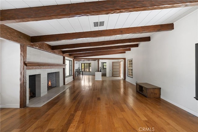 unfurnished living room with hardwood / wood-style flooring, a large fireplace, and beam ceiling