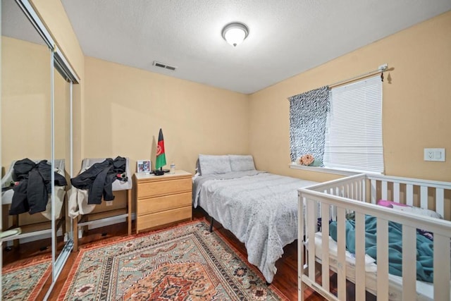 bedroom featuring wood-type flooring, a textured ceiling, and a closet