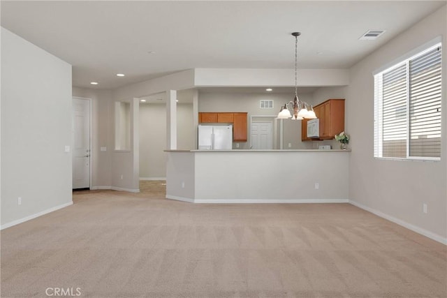 unfurnished living room featuring an inviting chandelier and light carpet